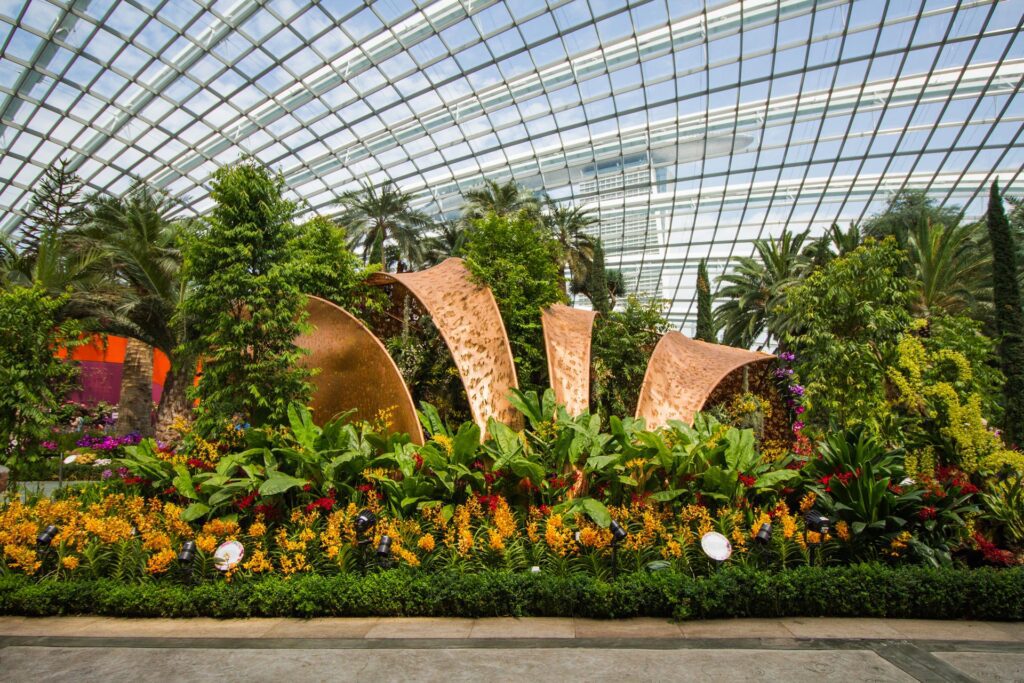 A lush Singapore butterfly garden with vibrant tropical flowers in bloom, attracting a variety of butterflies with brightly patterned wings.